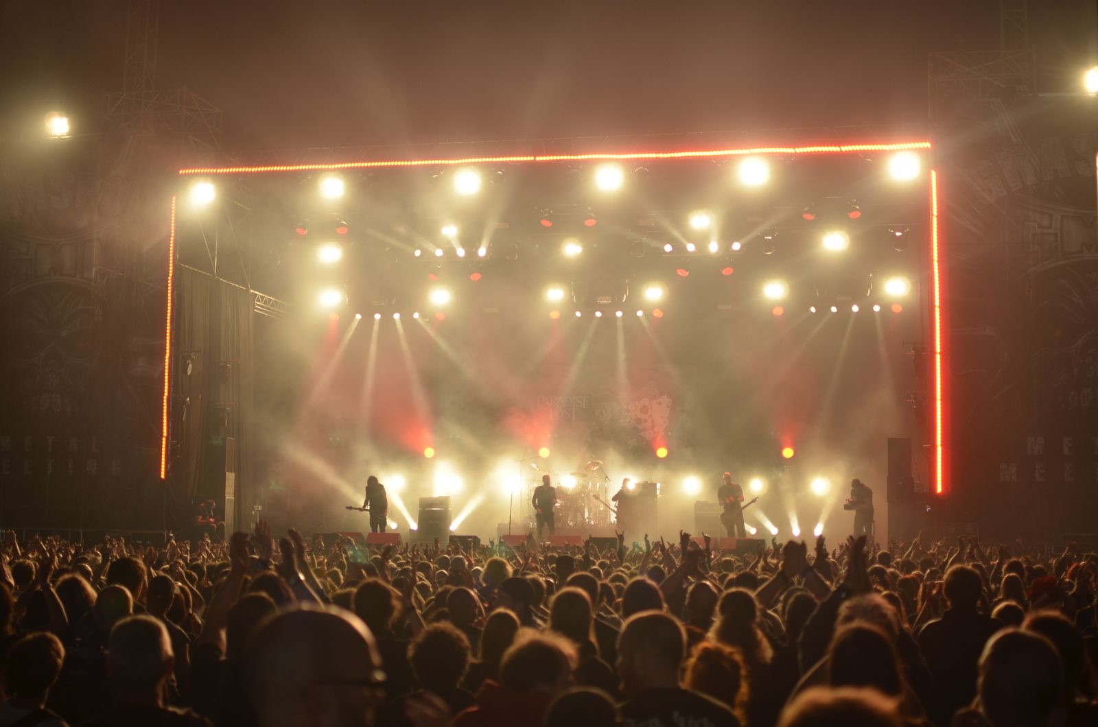 A crowd at a live show, hands raised under stage lights